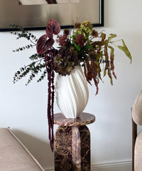 Kunstblumenstrauß Forest Ember in Bordeaux, Grün & Braun aus der Serie Bloom – auf dem Marmorsockel im Wohnzimmer