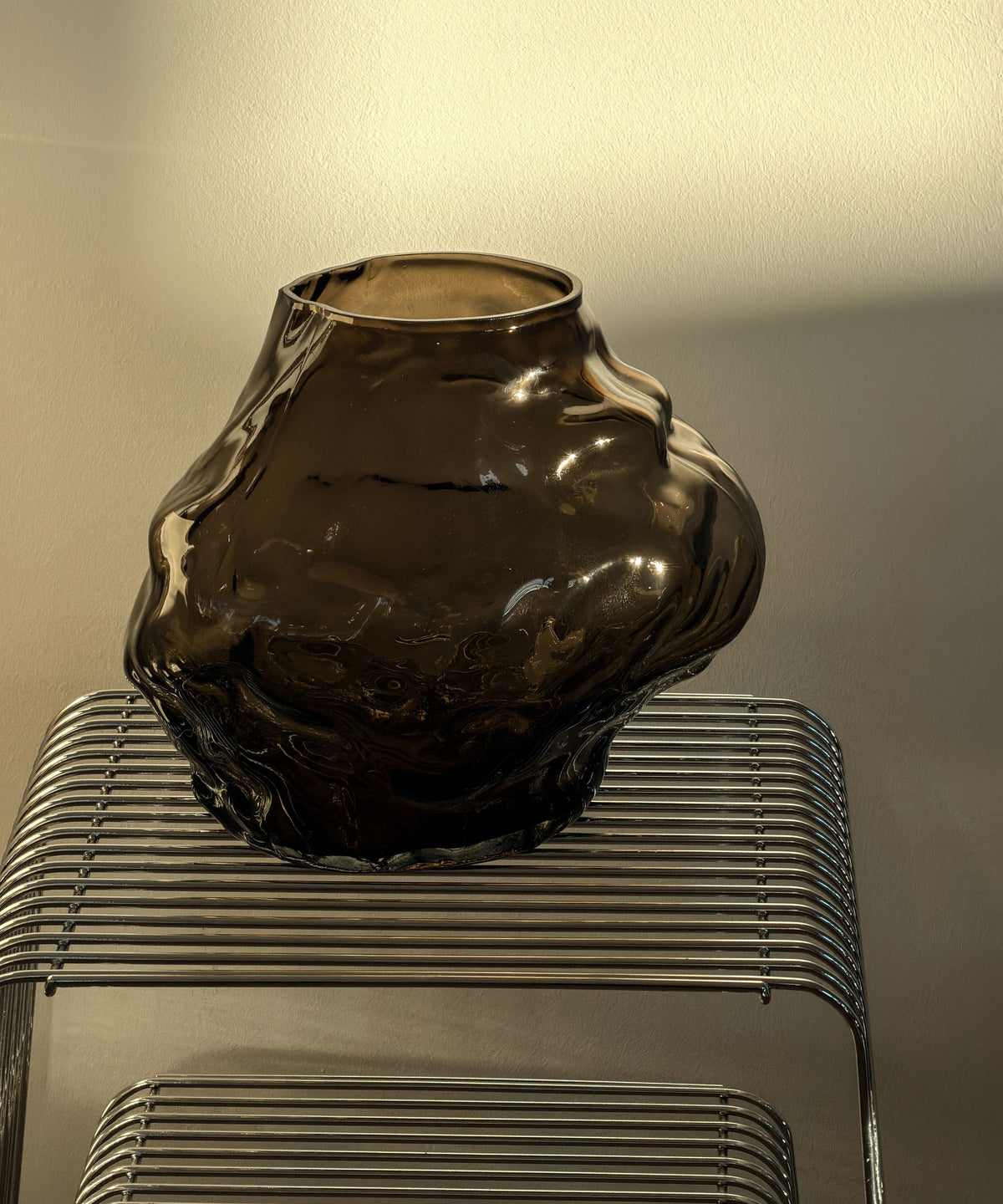 Suri Glasvase aus braunem Rauchglas auf dem Drahttisch im warmen Abendlicht